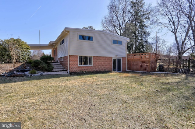 rear view of property with a lawn, brick siding, and a wooden deck