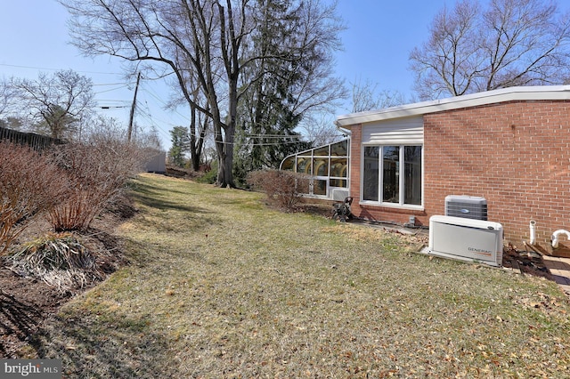 view of yard with central AC unit and a sunroom