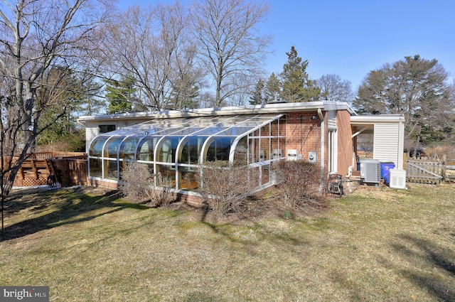 exterior space with central AC unit, a yard, fence, and brick siding