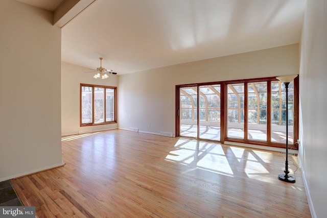 empty room with a wealth of natural light, light wood-type flooring, baseboards, and visible vents