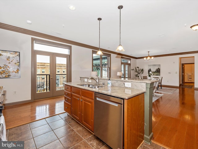 kitchen featuring light stone countertops, a sink, hanging light fixtures, stainless steel dishwasher, and brown cabinets