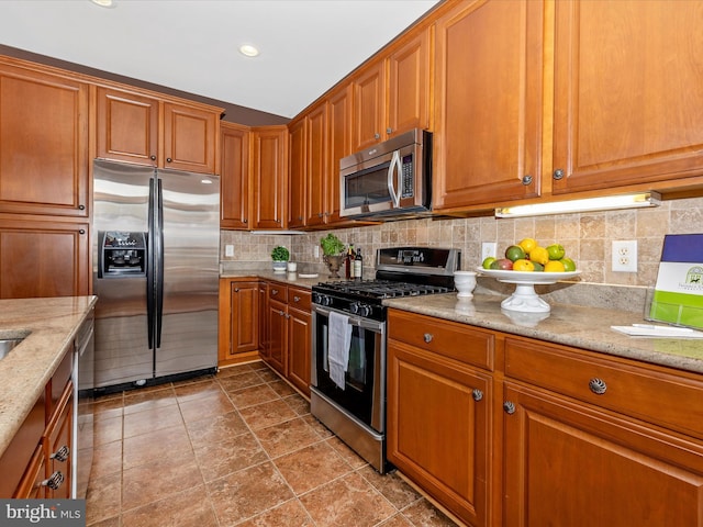 kitchen with light stone countertops, recessed lighting, appliances with stainless steel finishes, backsplash, and brown cabinets