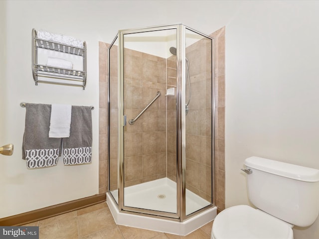 full bath featuring a stall shower, tile patterned flooring, toilet, and baseboards