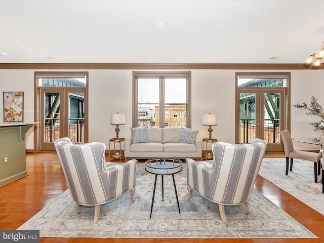 living area featuring light wood-style flooring, baseboards, and french doors