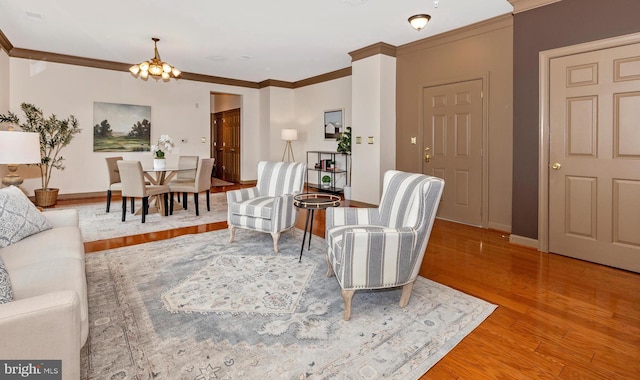 living area with a notable chandelier, baseboards, wood finished floors, and ornamental molding