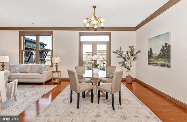 dining room featuring a chandelier, plenty of natural light, wood finished floors, and crown molding