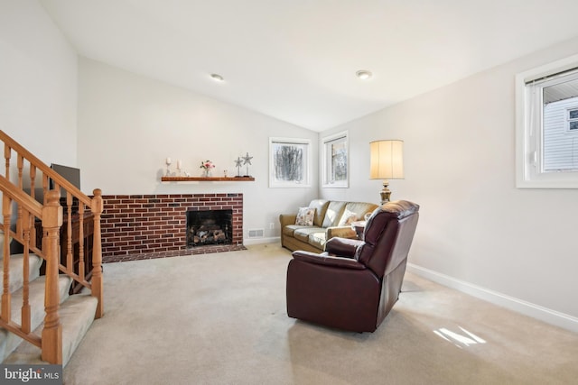 carpeted living area with a brick fireplace, stairway, lofted ceiling, and baseboards