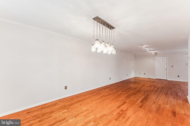 unfurnished room with ornamental molding, light wood-style flooring, and baseboards