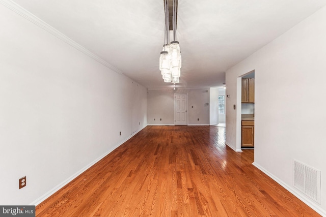 unfurnished dining area featuring a notable chandelier, wood finished floors, visible vents, and baseboards