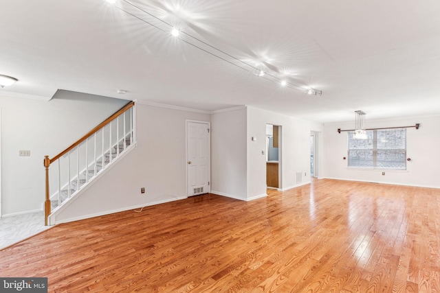 unfurnished room with crown molding, stairway, baseboards, and light wood-style floors