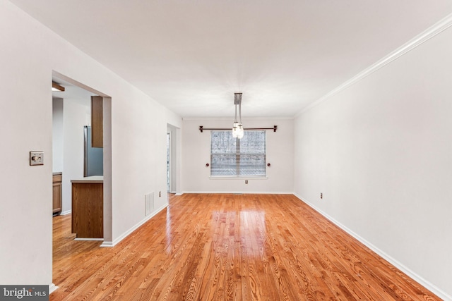 unfurnished dining area with light wood-type flooring, baseboards, visible vents, and ornamental molding