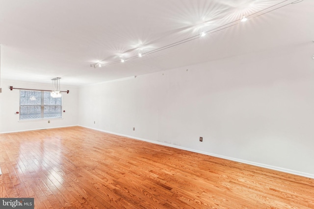 spare room featuring baseboards, crown molding, and light wood finished floors