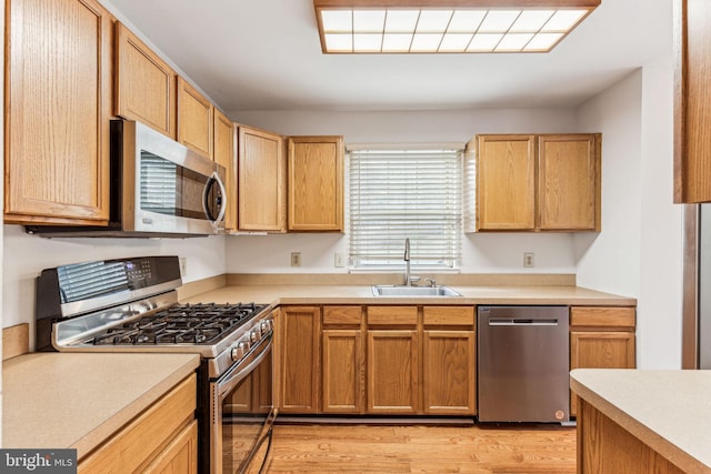 kitchen with light countertops, appliances with stainless steel finishes, a sink, and light wood-style flooring