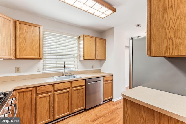 kitchen featuring light countertops, appliances with stainless steel finishes, light wood-type flooring, and a sink