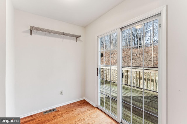 unfurnished room featuring light wood-style floors, visible vents, and baseboards