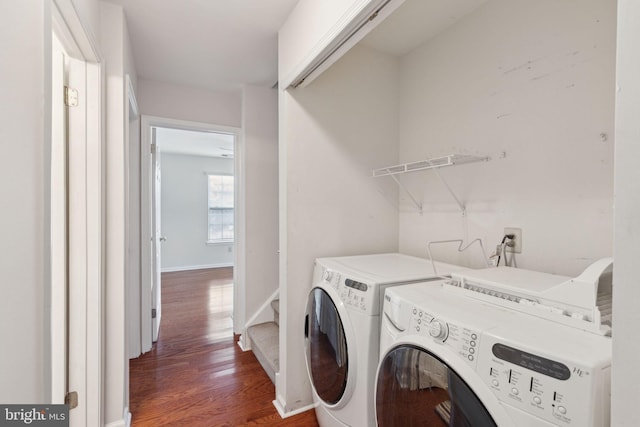 clothes washing area with laundry area, washing machine and dryer, baseboards, and dark wood-type flooring