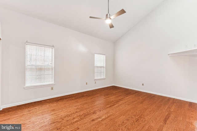 spare room with high vaulted ceiling, wood finished floors, a ceiling fan, and baseboards