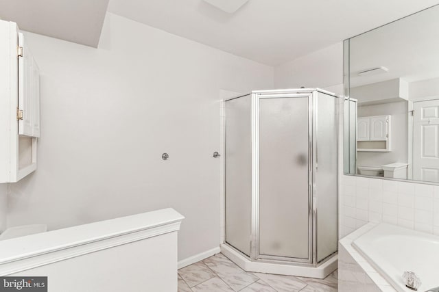 bathroom featuring a stall shower, baseboards, toilet, marble finish floor, and a bath