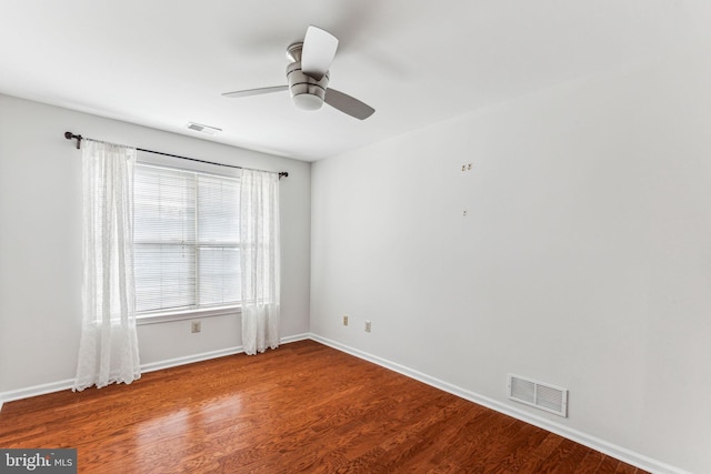 unfurnished room with a ceiling fan, visible vents, baseboards, and wood finished floors