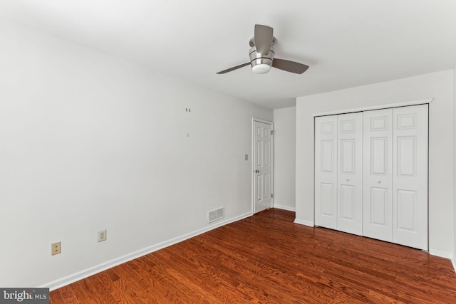 unfurnished bedroom featuring a closet, visible vents, dark wood-type flooring, ceiling fan, and baseboards