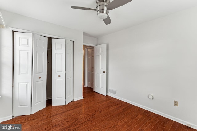 unfurnished bedroom with dark wood-style floors, baseboards, visible vents, and a closet