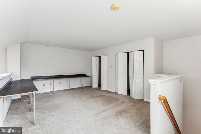 unfurnished bedroom with light colored carpet, vaulted ceiling, and two closets