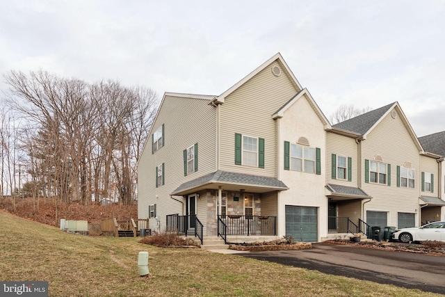 view of front of home with a porch, aphalt driveway, a garage, central AC, and a front yard