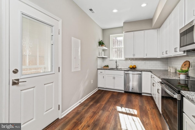 kitchen with dark wood-style flooring, a sink, white cabinetry, appliances with stainless steel finishes, and dark stone counters