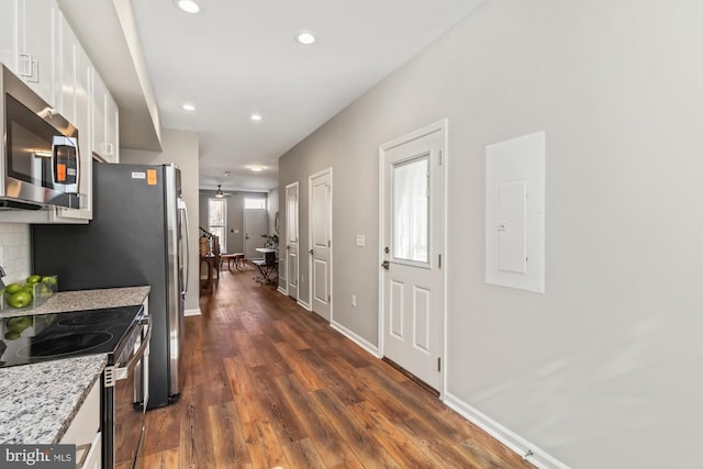 kitchen featuring light stone countertops, white cabinetry, appliances with stainless steel finishes, electric panel, and decorative backsplash