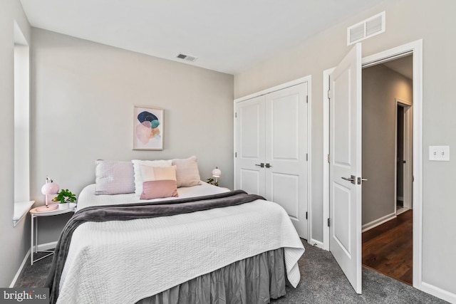 bedroom featuring dark colored carpet, a closet, visible vents, and baseboards