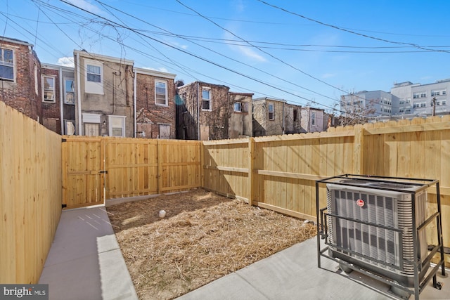 view of yard featuring a residential view, a gate, a fenced backyard, and central air condition unit