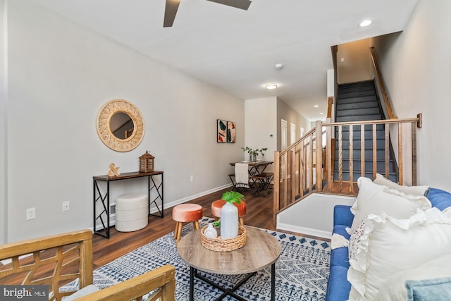 living room with a ceiling fan, wood finished floors, baseboards, and stairs