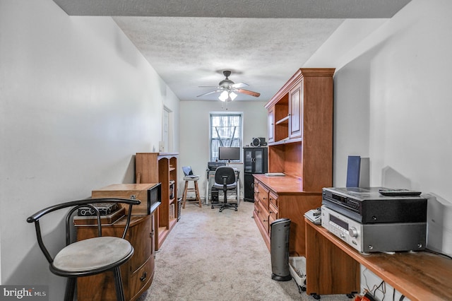 home office featuring ceiling fan, a textured ceiling, and light colored carpet