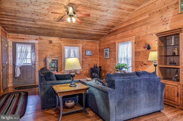 living room featuring vaulted ceiling, a wood stove, wood-type flooring, and wooden ceiling