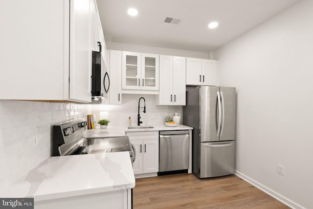 kitchen with stainless steel appliances, white cabinetry, a sink, and tasteful backsplash