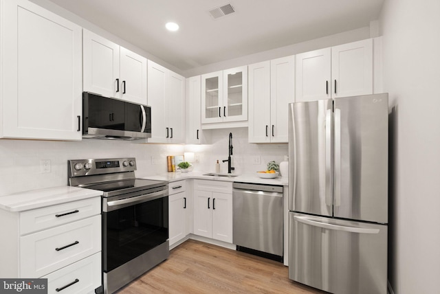 kitchen with a sink, visible vents, white cabinets, light countertops, and appliances with stainless steel finishes