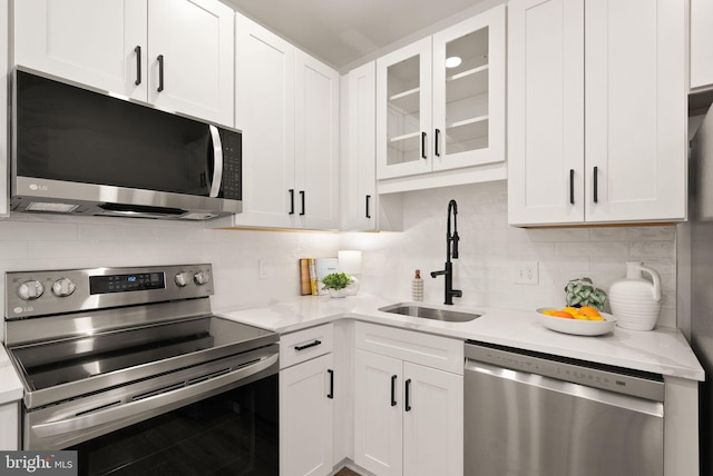 kitchen with stainless steel appliances, white cabinets, a sink, and backsplash