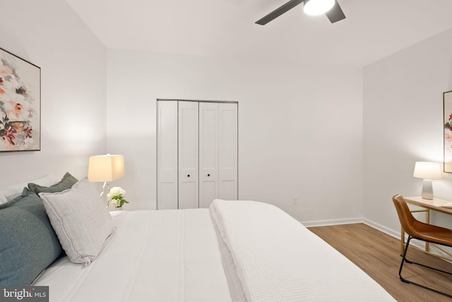 bedroom featuring a closet, wood finished floors, a ceiling fan, and baseboards