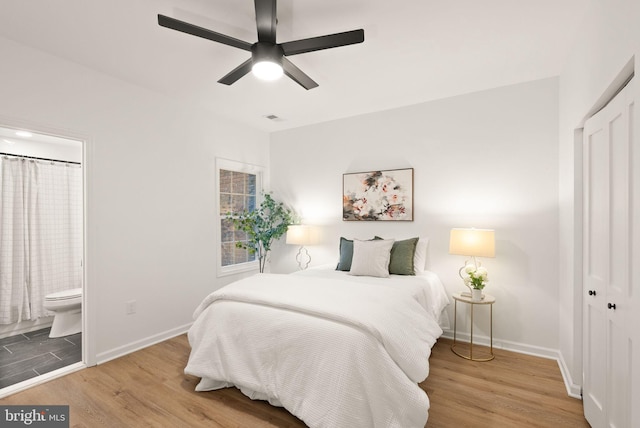 bedroom with visible vents, connected bathroom, baseboards, and wood finished floors