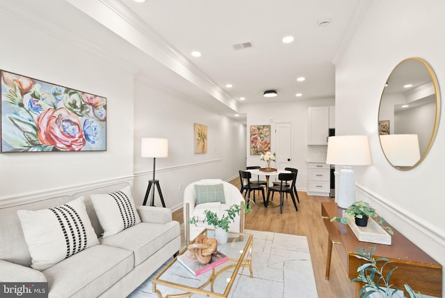 living area featuring light wood finished floors, recessed lighting, visible vents, and ornamental molding