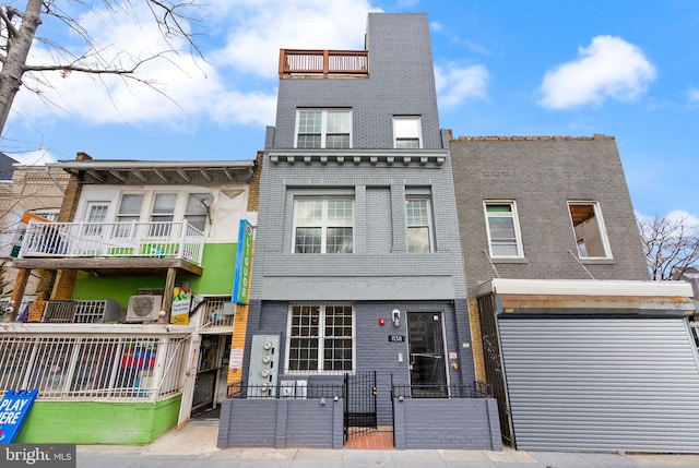 townhome / multi-family property with a fenced front yard, a gate, and brick siding