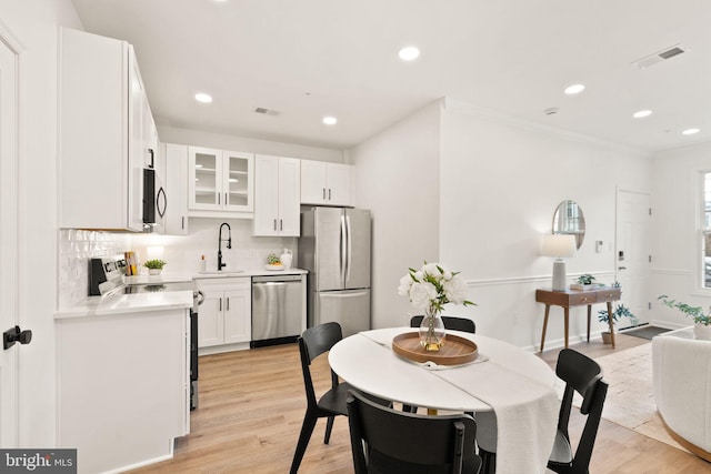 kitchen with stainless steel appliances, tasteful backsplash, light countertops, visible vents, and a sink