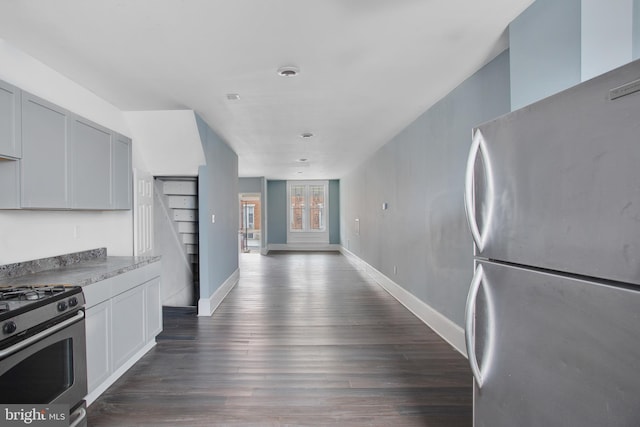 kitchen featuring dark hardwood / wood-style flooring, stainless steel appliances, and light stone counters