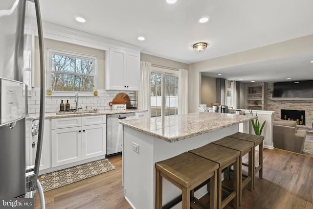 kitchen featuring appliances with stainless steel finishes, white cabinetry, light stone counters, and sink