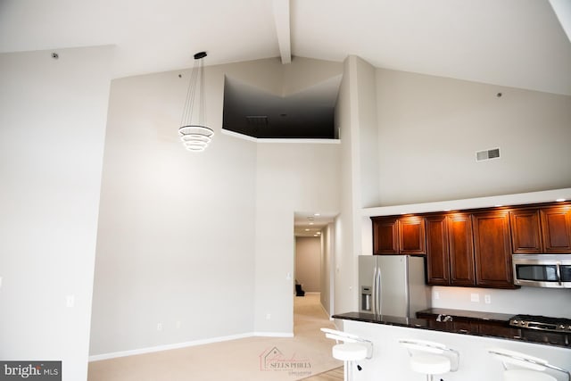 kitchen featuring high vaulted ceiling, beamed ceiling, stainless steel appliances, and decorative light fixtures