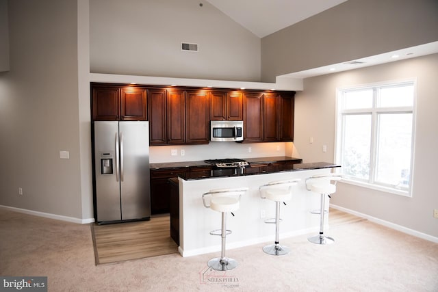 kitchen with a center island, appliances with stainless steel finishes, a breakfast bar area, and light colored carpet