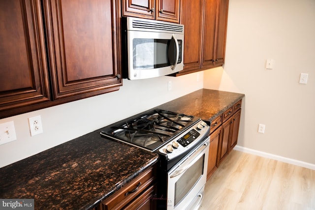 kitchen featuring dark stone countertops, stainless steel appliances, and light hardwood / wood-style flooring