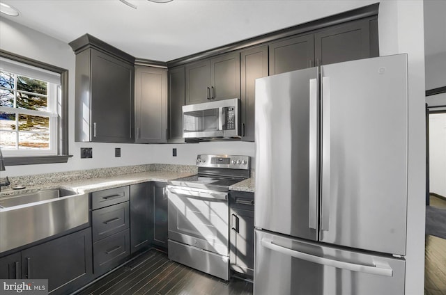 kitchen with sink, dark hardwood / wood-style flooring, stainless steel appliances, and light stone counters