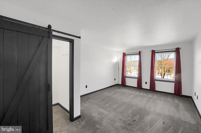 interior space with carpet floors, a textured ceiling, and a barn door