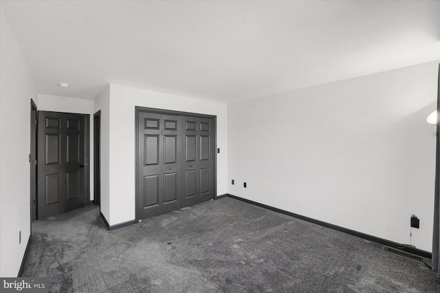 unfurnished bedroom featuring a closet and dark colored carpet